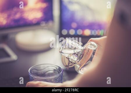 Drinking water in the office: close up of glass bottle, workplace Stock Photo