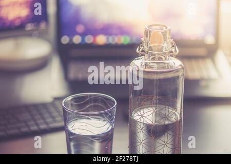 Drinking water in the office: close up of glass bottle, workplace Stock Photo