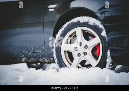 Car tire in winter on the road covered with snow, close up picture Stock Photo