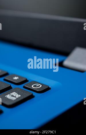 Closeup of a black power button on a blue laptop in a office Stock Photo