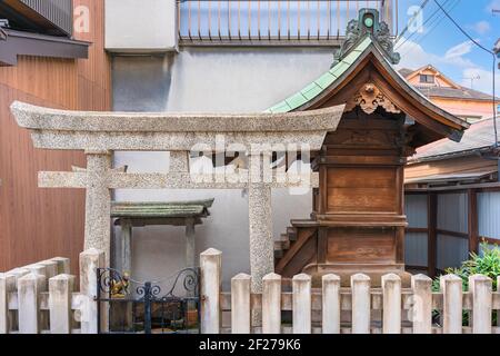 tokyo, japan - march 10 2021: Japanese shintoist stone torii gate and small massha wooden altar dedicated to the Inari fox shinto kami god of rice in Stock Photo