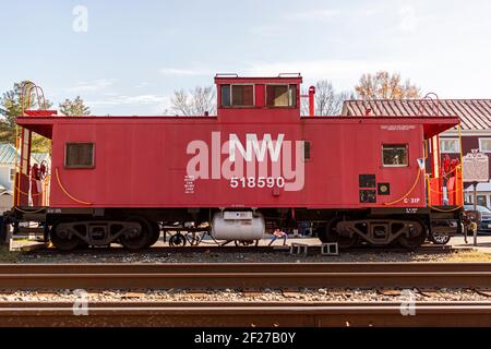 Clifton, VA, USA 11-14-2020: A red vintage caboose placed by the train tracks in front of the historic Devereux Station in scenic Clifton. This is an Stock Photo