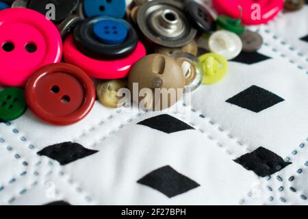 Some different colorful buttons on white, big and soft surface with some black diamonds in a straight line Stock Photo