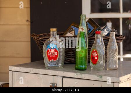 Clifton, VA, USA 11-14-020: A set of vintage empty glass bottles of beverages (Bicentennial Log Cabin Syrup flask, pepsi and Dr. Pepper bottles) are p Stock Photo