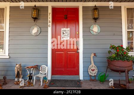 Clifton, VA, USA, 11-14-2020: Entrance of a colonial era house in historic town. Red door has a sign saying Come in for a spell with a witch symbol on Stock Photo