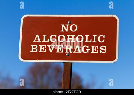 A brown metal plate with 'No Alcoholic Beverages' notice on. This sign post is put on public areas and parks to restrict consumption of alcohol by vis Stock Photo