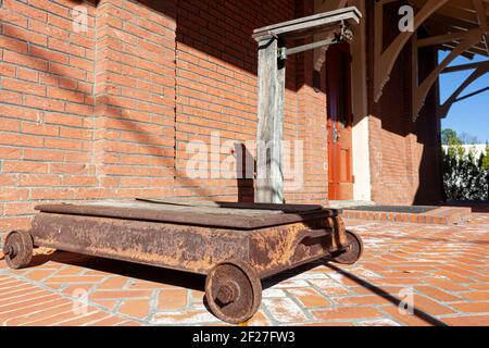 A vintage rusty industrial size platform scale with metal wheels and a beam balance. This antique item is on display on the platform of historic 19th Stock Photo