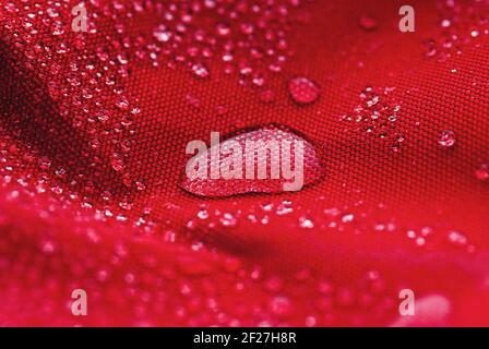 Large water drop on red waterproof fabric Stock Photo