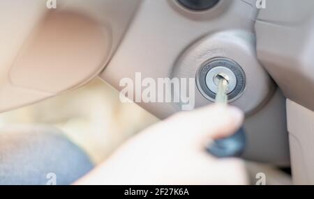 Close up the female hand use the car key into the keyhold preparing to start a car. Stock Photo
