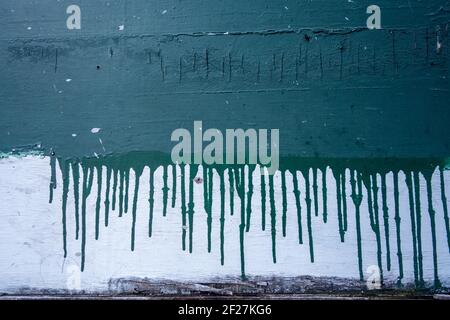 a white painted wall with green paint dripping over it Stock Photo