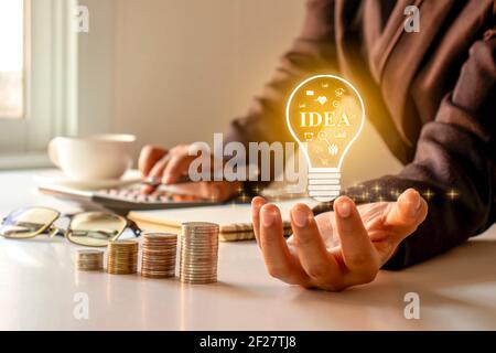 Businessman holding a light bulb, ideas on his desk, ideas for finance, investment and running a successful business. Stock Photo