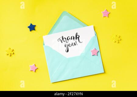 Thank You card in a teal blue envelope, shot from above on a yellow background Stock Photo