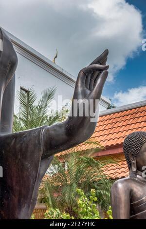 The out stretched hand of a Leela attitude Buddha over the Forest Monk Buddha statue outside the Thai Buddhist Temple, Wat Buddharangsi of Miami, loca Stock Photo