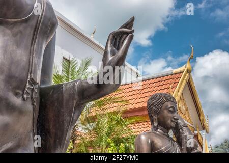 The out stretched hand of a Leela attitude Buddha over the Forest Monk Buddha statue outside the Thai Buddhist Temple, Wat Buddharangsi of Miami, loca Stock Photo