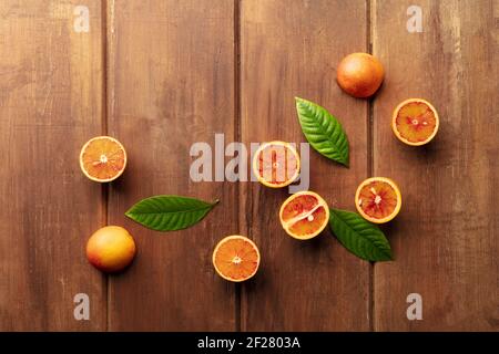 Organic blood oranges, shot from the top on a dark rustic wooden background with green leaves Stock Photo