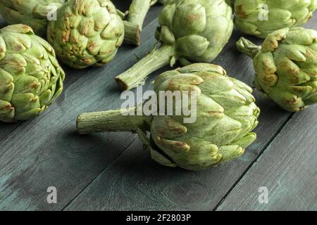 A closeup of a globe artichoke on a dark rustic wooden background Stock Photo