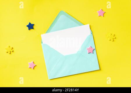A greeting card in a blue envelope, shot from the top on a yellow background Stock Photo