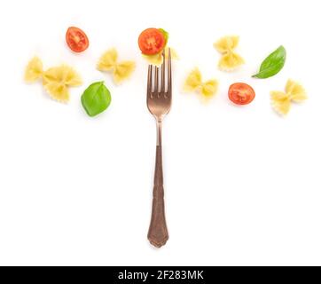 Italian pasta. An overhead photo of a vintage style fork with farfalle, basil, and cherry tomatoes on a white background Stock Photo