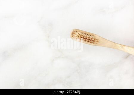 A closeup of an organic biodegradable bamboo toothbrush on a white marble background Stock Photo