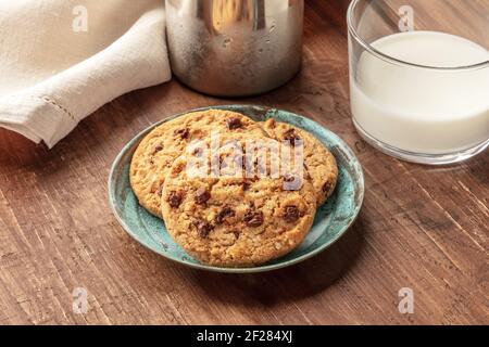 A closeup photo of chocolate chip cookies with milk on a dark rustic wooden background Stock Photo