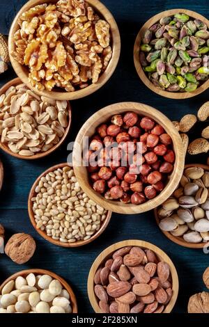 Various nuts, shot from the top in wooden bowls on a dark background Stock Photo