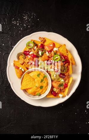 Nachos with beef, guacamole and cheese sauce, top shot on a black background Stock Photo