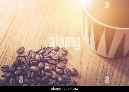 Close up of fresh roasted coffee beans and coffee mug on wooden background Stock Photo