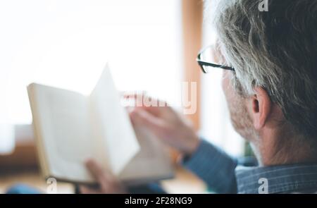 Senior man is reading a book at home, selective focus Stock Photo