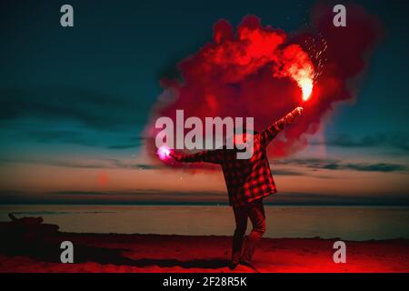 Man with torch fire in hands goes at sunset lake beach Stock Photo