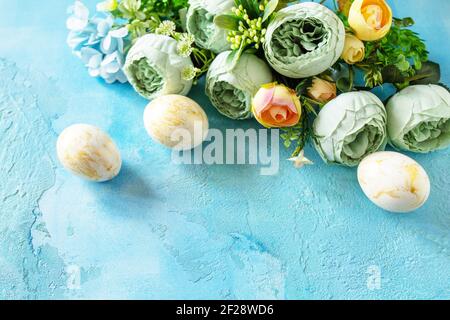 Happy Easter background. Spring flowers and Easter eggs on a concrete blue background. Stock Photo