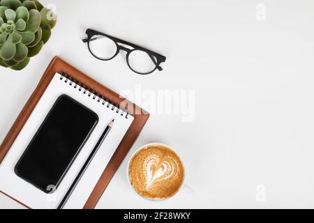 office table desk, workspace with mobile phone, notebook, pencil, green plant, coffee and eyeglass. Business background. Flat lay, top view.copy space Stock Photo
