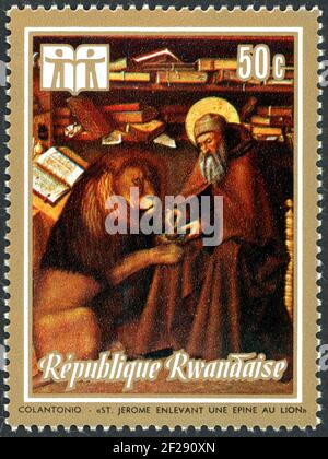 RWANDA - CIRCA 1973: A stamp printed in Rwanda, shown the painting by Colantonio - St. Jerome Removing Thorn from Lion’s Paw, circa 1973 Stock Photo