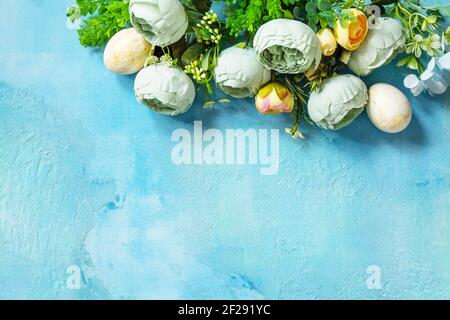 Happy Easter background. Spring flowers and Easter eggs on a concrete blue background. Top view flat lay. Stock Photo