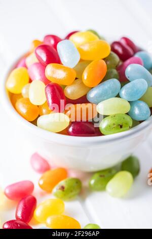 Sweet colorful jelly beans in bowl on white table. Stock Photo