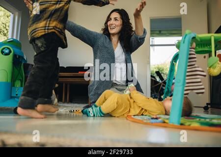 Mother playing with her two kids at home. Woman on maternity leave spending time with her children indoors. Stock Photo