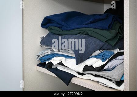 Clothes messy piled up on the closet shelf Stock Photo