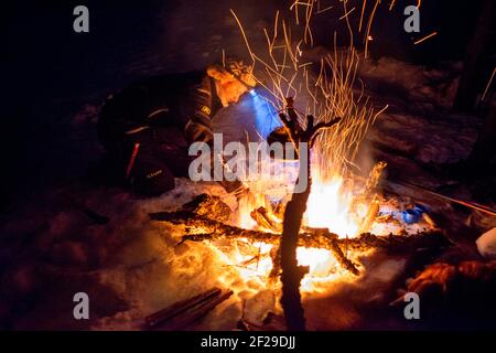Tea moment in the snow. Snowshoeing tour at night to see the Northern Lights in Mosjoen Norway.  Cooking pot on open fire Stock Photo