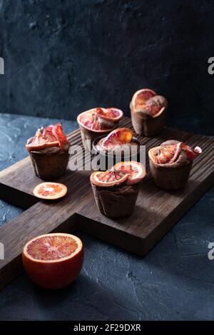 Blood oranges brownie muffins on dark oak cutboard and dark plaster background copyspace Stock Photo