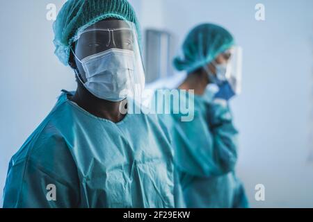 Doctors at work inside hospital during coronavirus outbreak - Medical worker on Covid-19 crisis wearing safety protective mask - Focus on african man Stock Photo