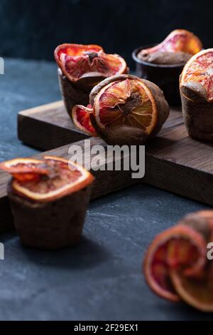 Blood oranges chocolate brownie muffins at brown oak cutboard on dark plaster background close up Stock Photo