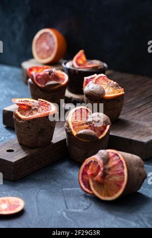 Blood oranges choco muffins close up at dark oak cutboard on dark cocrete background Stock Photo