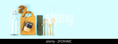 Banner made from eco bags with bamboo cutlery, reusable coffee mug and water bottle on blue background. Sustainable lifestyle. Zero waste and plastic Stock Photo