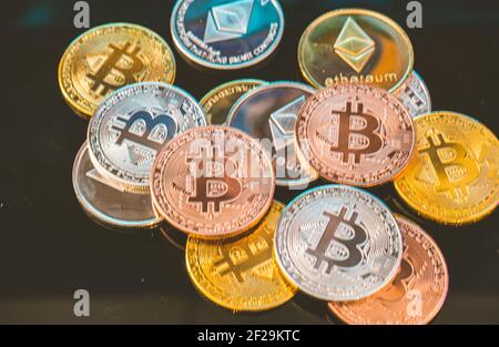 Money, Bitcoin gold, silver and copper coins and defocused printed circuit background. Virtual cryptocurrency concept. Stock Photo