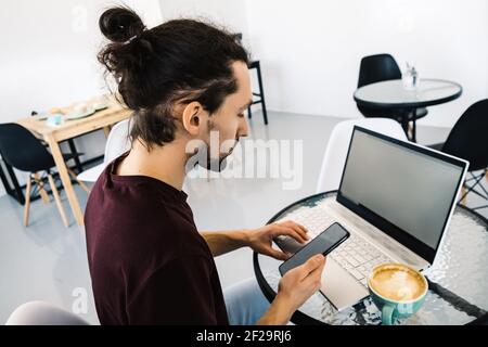 Freelance man working with laptop and smart phone at cafe with coffe. Stock Photo