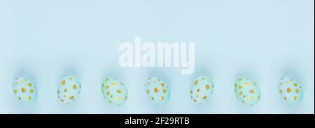 Easter banner - blue eggs with golden dots in row as border on blue backdrop, top view, copy space. Stock Photo
