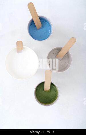 The process of creating a painting using the fluid art technique. Four glasses with paints. Stock Photo