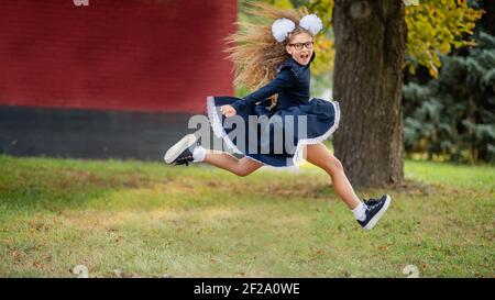 Portrait of beautiful young Schoolgirl on background school. Farewell Bell. day of knowledge. beginning of school year. Holidays. Hooray, holidays Stock Photo