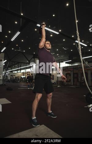 Full length shot of a muscular young man exercising with kettlebell at the gym Stock Photo