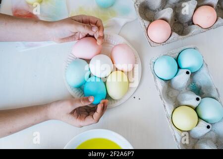 Flat lay Easter background. Close up Child holding colorful dyed easter eggs in her hands. View from above, pastel colors Stock Photo