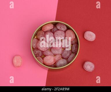 fruit oval lollipops in an open round tin can on a red background, top view Stock Photo
